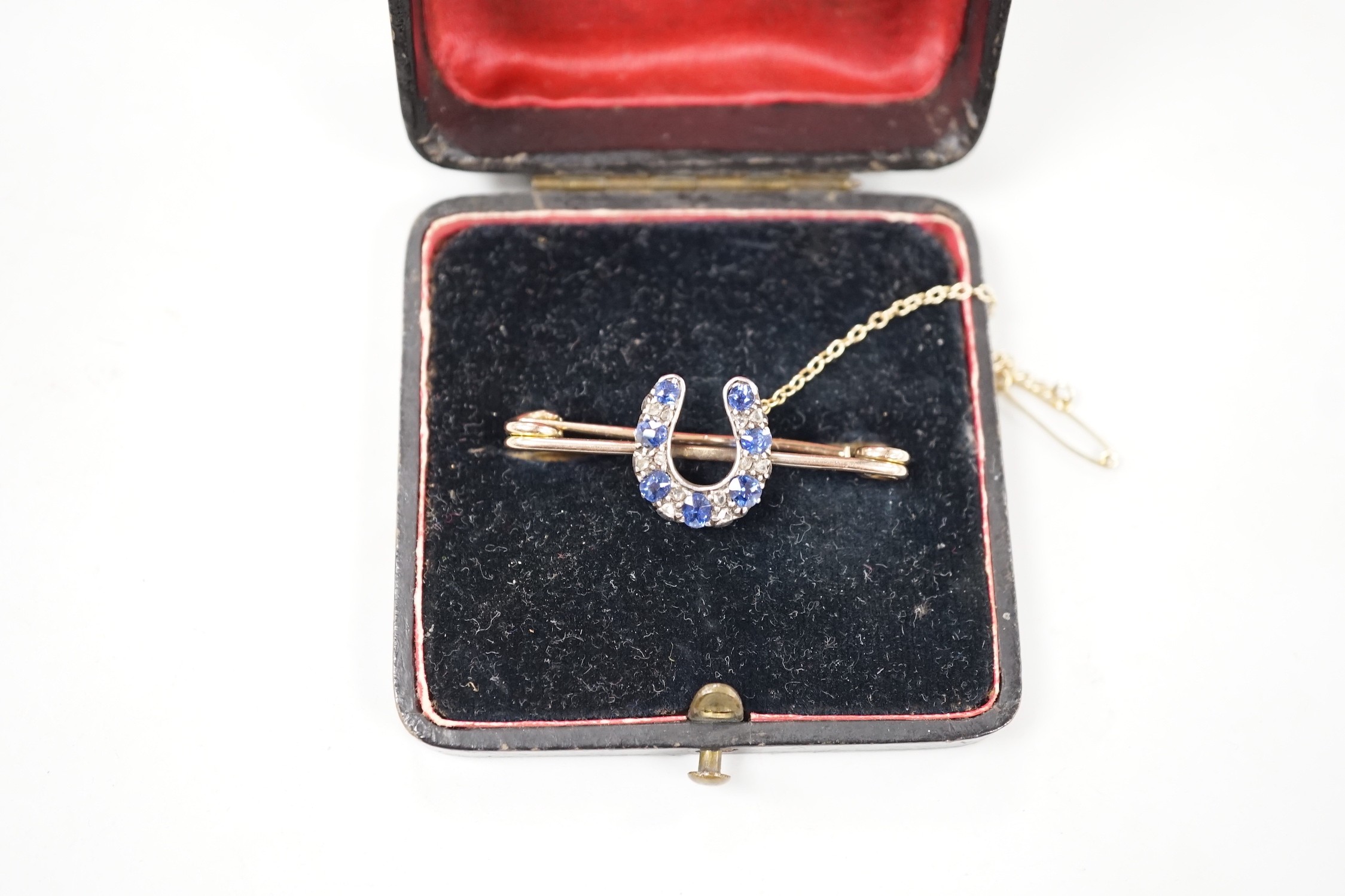 A late Victorian yellow metal. sapphire and diamond cluster set horseshoe bar brooch, 42mm, gross weight 5.3 grams.
